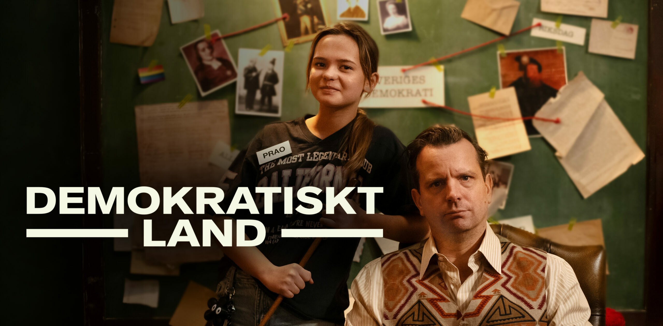 Praoelev och lärare sitter i klassrum och tittar mot kameran.